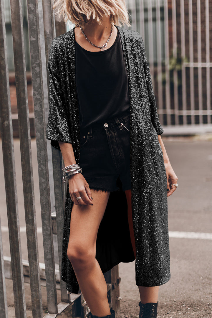 trendy stylish young girl leans on iron fence wearing a sequin floor duster outside with bangle bracelets on